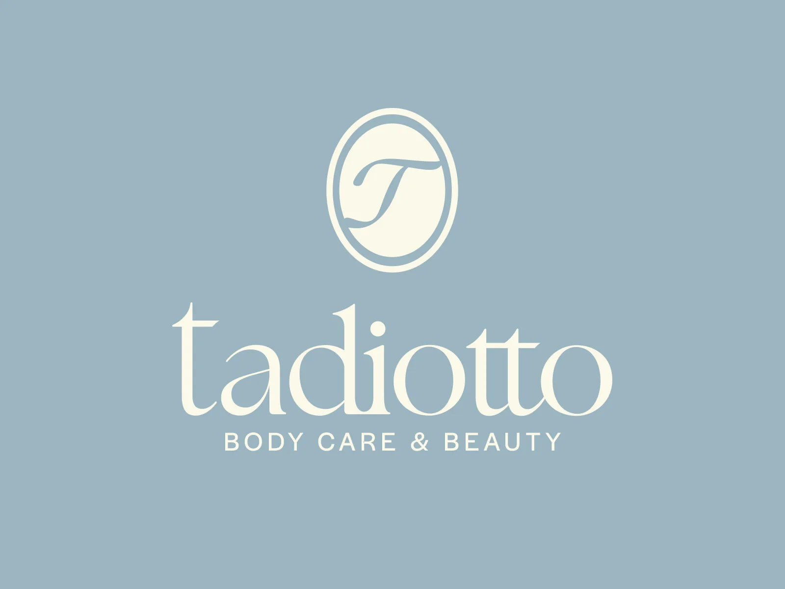 Marca Tadiotto Body Care & Beauty, com o monograma, em creme sobre fundo azul-acinzentado